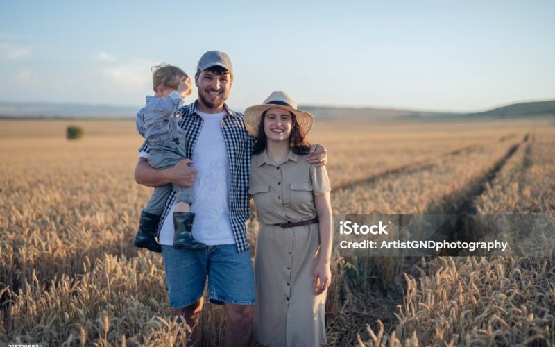 Portrait of young,beautiful farm family standing in agriculture field.