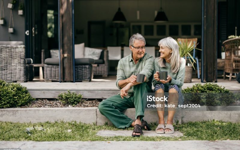 With coffee in hand, a senior couple in their 60s embraces a quiet moment, appreciating the beauty of their home.